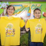 boy and girl hold up summer reading club shirts