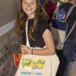 Young patron wears and shows off tote bag