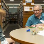 young patron and adult do origami paper craft together