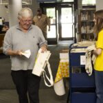 Adult patron picks up cookie and tote back at summer reading kickoff party