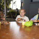 teens sit and enjoy pizza