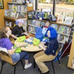 teens sit at table to eat pizza and play tabletop game