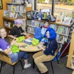 teens sit at table to eat pizza and play tabletop game