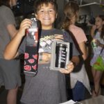 Golden ticket winner holds up his socks & cup prize