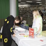 teen dressed as Pokemon examines scavenger hunt booth