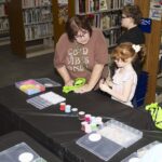 adult and girl make bracelets
