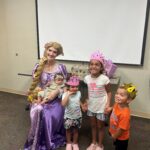 young children in tiaras and a crown pose with Princess Rapunzel