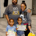 Family smiles. Two young boys hold their Imagination Graduation diplomas