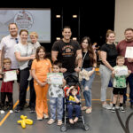 Group shot of adults with kids. Some kids hold up their Imagination Graduation diplomas