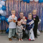 Family poses in front of decorated photo station