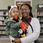 Woman holding young girl. Young girl smiles and holds a Minnie Mouse plushie