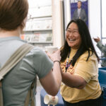 Stack Manager Sara Martindale smiling as she hands out mugs to patrons