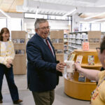 Librarian hands man in suit a "See Ya at Xenia" mug