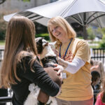 Head Librarian Melissa F. pets a goat on the patio