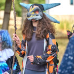 teen in dragon mask holds staff