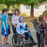 Teen in wheelchair with blue hair waiting in line for event