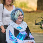 Teen in wheelchair with blue hair waiting for event entry