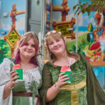 two teens dressed in renaissance dresses enjoying snow cones