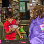 teen reading paper to librarian
