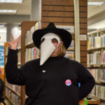 Teen dressed as plague doctor throws up a peace sign