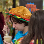 Teen in hamburger hat drinks butter beer float