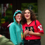 two teen girls smile and pose in front of entrance