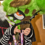 teen in furry mask makes a beaded necklace