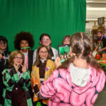 group of dressed up teens pose in front of green screen