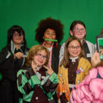 group of dressed up teens pose in front of green screen
