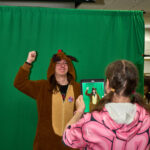 Teen in reindeer onesies poses in front of green screen