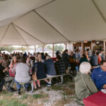 groups sitting at tables under tent