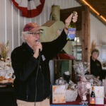 winery owner raising wine bottle