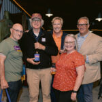group smiling while man holds wine
