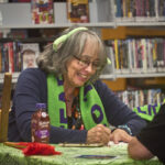 Librarian Karen Tracy Jeffers wearing her terrifying trivia scarf, writing something down