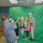 patrons posing in their scarves at the green screen